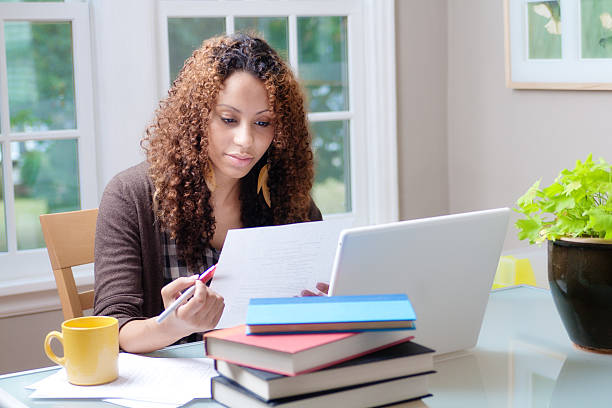 A young black female woman working in dorm room in university, or home office.